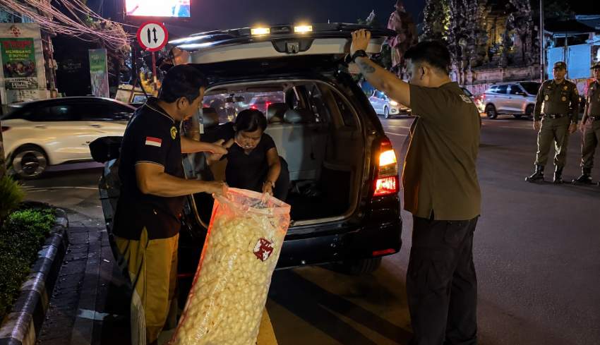 Agents de la police municipale de Denpasar en patrouille de contrôle de la circulation routière et de l'ordre public dans un carrefour urbain.